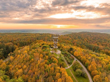 Majestic tower amidst a vibrant autumn forest under a dramatic sunset sky, Schönbuchturm,