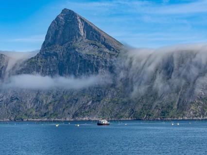 Salmon farm, aquaculture in the Mefjord on Senja island, in the background the peak of famous Segla