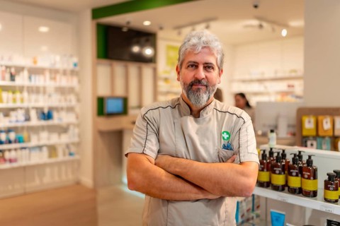Proud mature man pharmacist standing with arms crossed in the store