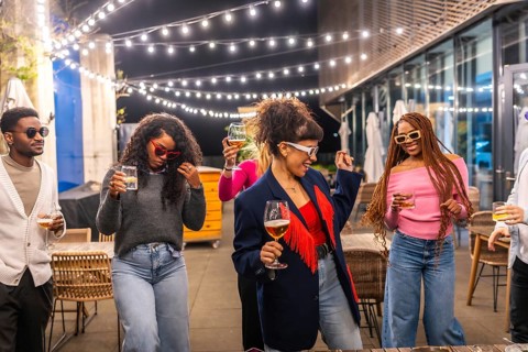 Group of young multi-ethnic friends dancing and drinking at outdoor night party