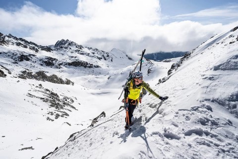 Mountaineer with skis climbing up a steep snow slope to the fork Porta d'Es-cha, ski tour Bündner