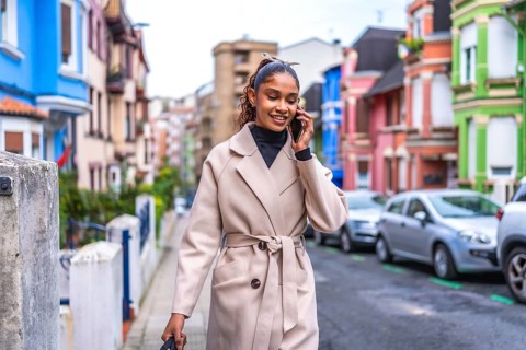 Stylish and beauty african american businesswoman wearing trench coat talking to the mobile phone
