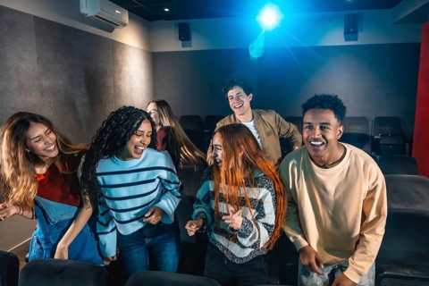Happy multi ethnic friends dancing and celebrating together at a lively movie disco event in the