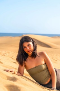 Young woman lying on the sand in the maspalomas dunes, gran canaria, canary islands, spain,