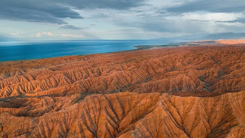Landscape of eroded hills, badlands at sunset, Issyk Kul Lake in the background, aerial view,