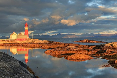 Lighthouse reflected in water, morning light, clouds, mountains, coast, Tranoy, Ofoten, Norway,