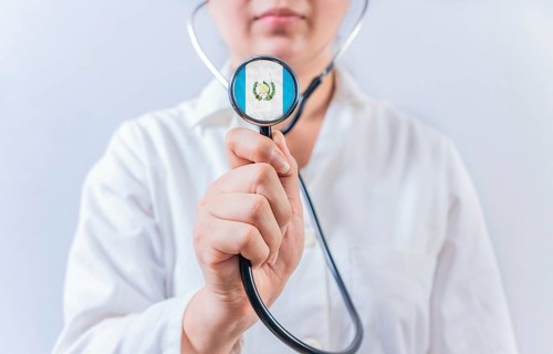 Female doctor holding stethoscope with Guatemala flag. Guatemalan Health and Care concept