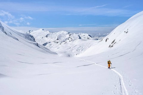 Lone ski tourer in a mountain landscape with snow, summit Wildhorn in the background, ascent to