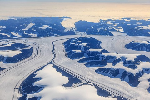 Aerial view of glaciers, glacier tongues and icy mountains on the coast, sunny, East Greenland,