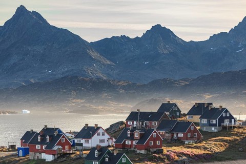 Typical Greenlandic houses on a fjord with steep mountains, Inuit settlement, autumn, Tasiilaq,