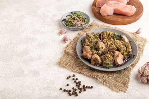 Stewed turkey fillet with garlic and sprouts of radish on white wooden background and linen textile