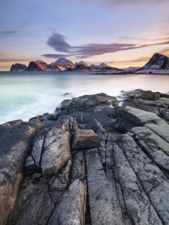 Rocky coast, snow-capped mountains in the background, Vestvågøya, Lofoten, Norway, Europe
