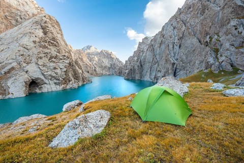 Green tent at the turquoise mountain lake Kol Suu with rocky steep mountains, Kol Suu Lake, Sary