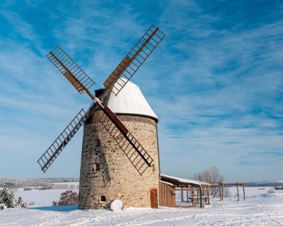 The tower windmill of Warnstedt in winter surrounded by snow-covered landscape under a blue sky,