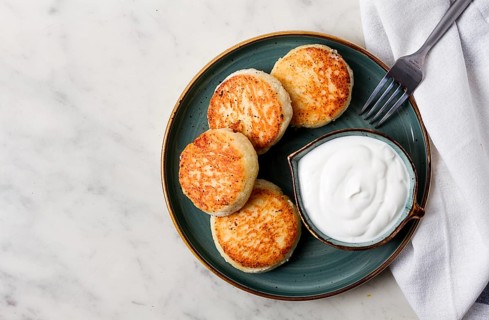 Fried, Cottage cheese pancakes, with sour cream, Cheesecakes, on a marble table, top view, no