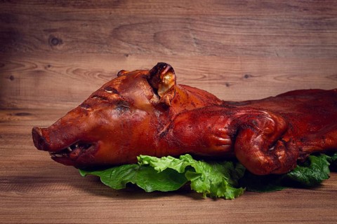 Baked, fried piglet, on a wooden table, no people, The whole piglet is baked and served on the