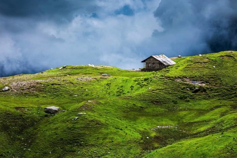 Serenity serene lonely scenery background concept, house in mountains on alpine meadow in clouds.