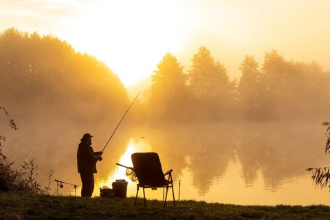 Angler on the bank at sunrise in the fog at the Grutschenteich in Nassau, Weinböhla, Saxony,