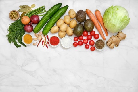 An assortment of vibrant farm vegetables and fresh herbs on a marble surface for healthy cooking