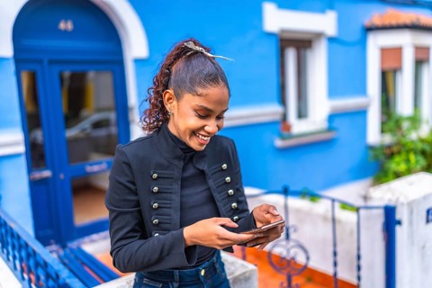 Happy and beauty african american woman using phone in a colorful street