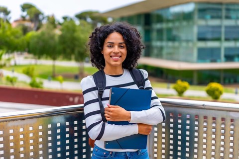 Portrait of a female smiling latin student with casual clothes and rucksack standing proud with