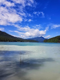 A clear lake with calm, blue water surrounded by mountains under a cloudy sky, Walchensee, Kochel