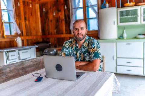 Digital nomad working on laptop in a cozy wooden cabin, embracing freedom and flexibility of remote
