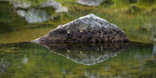A rock is reflected in the Obersee, Schladming, Styria, Austria, Europe