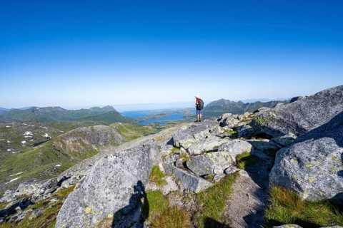 View of mountains and fjord landscape, mountaineer at the summit of Rundfjellet, Svolvaer,