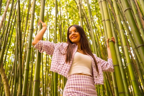 Young caucasian girl with a pink skirt in a bamboo forest. Enjoying summer holidays in a tropical