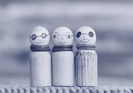 Three small funny wooden cones, monochrome in front of a painted background, North