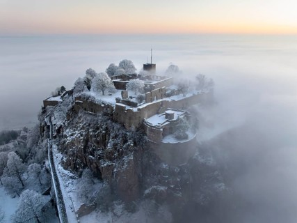 Aerial view of the Hegau volcano Hohentwiel with Germany's largest fortress ruins on a cold, foggy