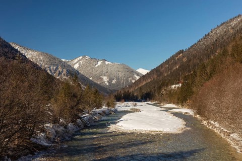 The Riss creek flowing through a snow covered landscape in the Eng valley. Sunny day with blue sky