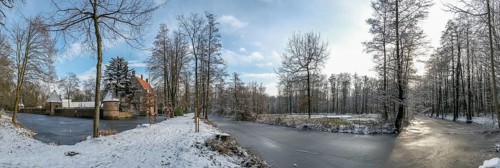 Wide winter landscape near moated castle Haus Welbergen with frozen water and trees,