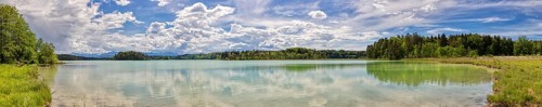 Lake with clear water surface, cloudy sky and surrounding green nature, Easter Lakes