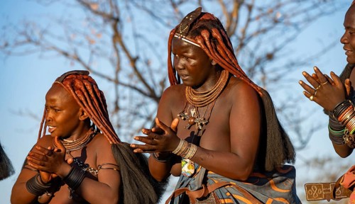 Traditional Himba woman clapping, music and dance, portraits, in the evening light, near Opuwo,