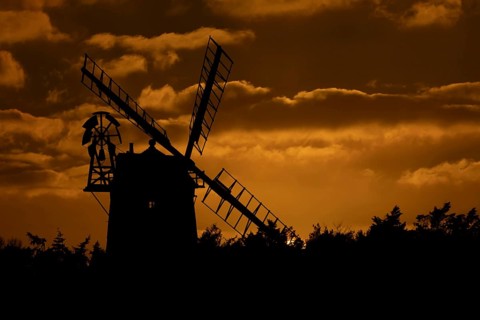 Windmill silhouette at sunset with a red sky and clouds behind, Cley-next-to-the-sea, Norfolk,