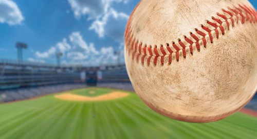 Baseball flying through the air with stadium in the background