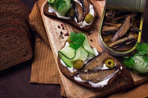 Sandwiches, black bread with sprats, cream cheese, cucumbers, on a cutting board, top view,