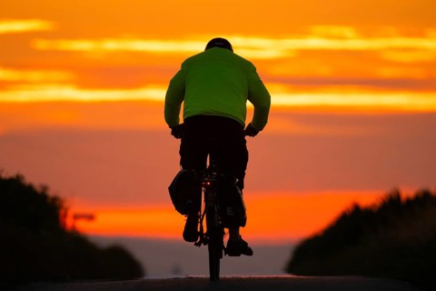 A cyclist rides towards the sunrise, Frankfurt am Main, Hesse, Germany, Europe