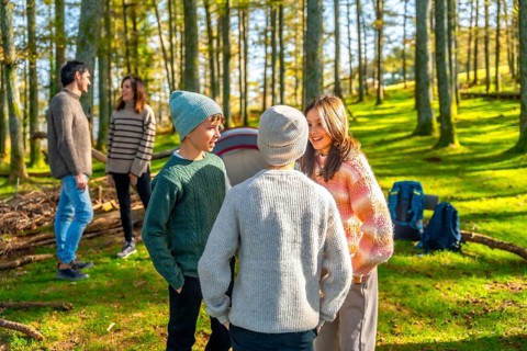 Caucasian family with three teens having fun during a camping in a green alpine forest