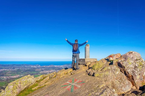 A male hiker celebrating the climb to the top of Mount Adarra in Urnieta. Gipuzkoa, Basque Country
