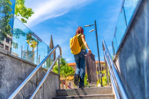 Low angle view photo of the rear view of a young woman with casual denim clothes and a bag carrying