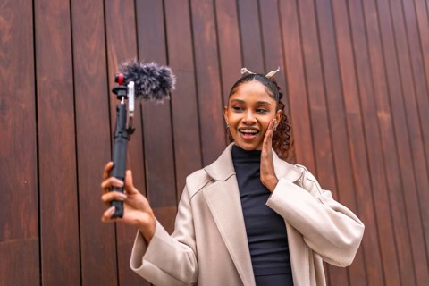 Cute and beauty african american woman recording vlog in the city next to a wooden wall