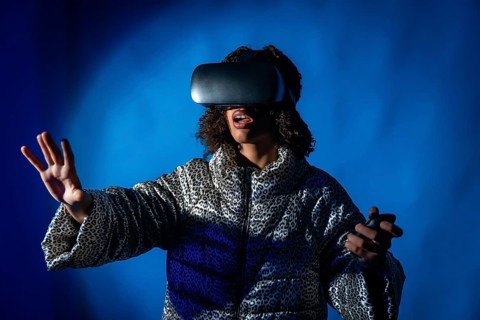 Young woman wearing a vr headset and holding controllers, expressing surprise while immersing in