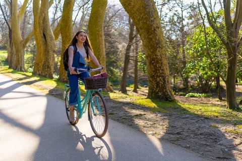 Student enjoying cycling in a park during a sunny spring day, promoting sustainable mobility and