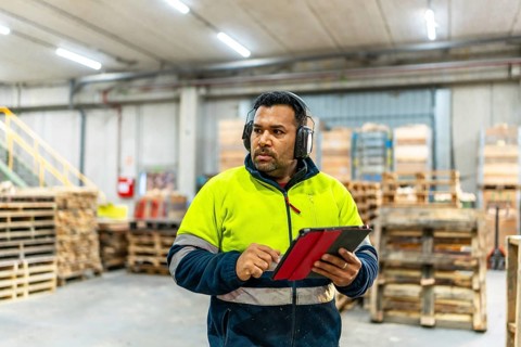 Man worker using digital tablet in the carpentry area of a recycling plant
