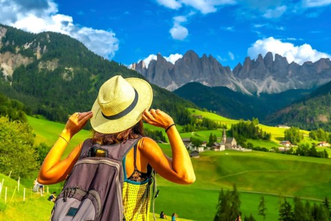 Female tourist holding her hat while admiring the stunning view of the odle mountains and santa