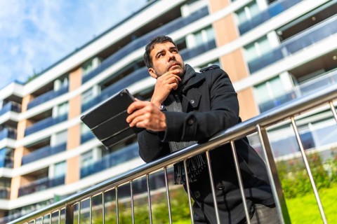 Low angle view potrait of a caucasian pensive businessman in casual winter clothes using digital