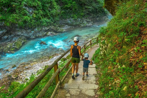 Tourists wearing helmets are enjoying a summer walk along the stunning turquoise radovna river